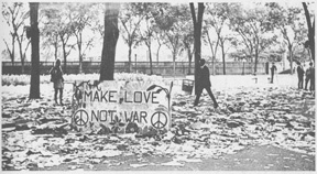 Large protester poster that reads, "Make Love, Not War," leaning against a tree in a Chicago park.